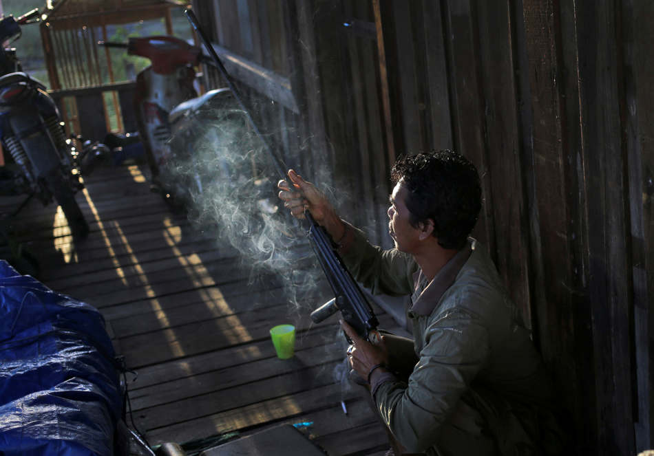 In this Jan. 5, 2016, photo, Tony Setiono, a conservationist from the Borneo Orangutan Survival Foundation, prepares a tranquilizer gun prior to a rescue and release operation for orangutans trapped in a swath of jungle in Sungai Mangkutub, Central Kalimantan, Indonesia. A team consisting of foresters, veterinarians and technicians were deployed to rescue orangutans which lost their habitat to the forest fires last year, and relocate them to a new location. (AP Photo/Dita Alangkara)