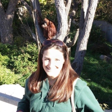 Debbie Clemens standing outdoors at a zoo habitat, supporting the Orangutan Outreach mission as Community Engagement Manager